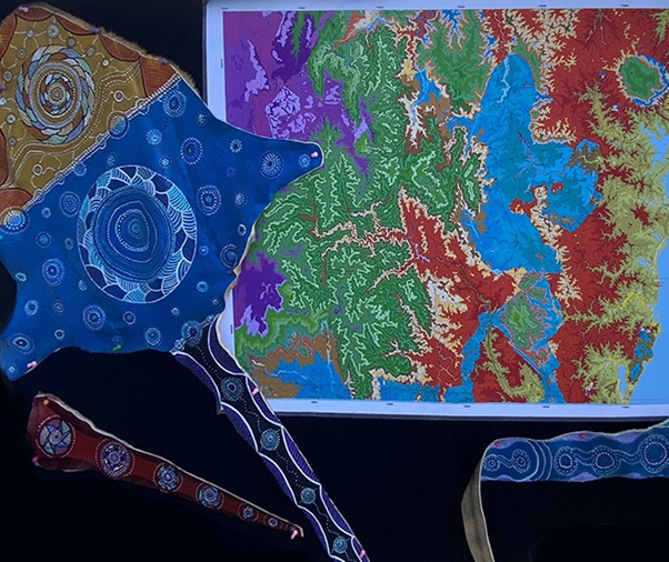 Aboriginal artwork on animal skin in front of colourful map